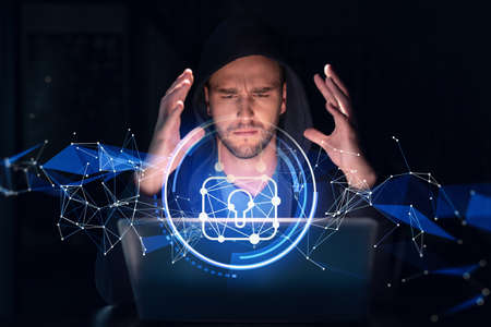 Handsome businessman in hoodie at workplace working with laptop to defend customer cyber security....