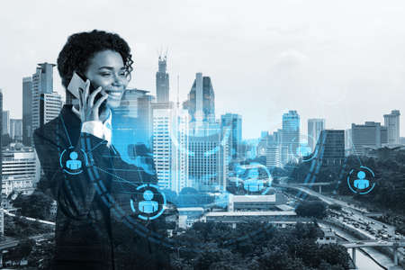 Attractive black woman new approaches to protect clients confidential information using phone. IT social network icons over Kuala Lumpur city background.の写真素材