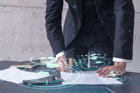 A client in dark blue suit is signing a contract to create a new software to present it in start up conference and gain investments to create a product. Technological graph over the desk.の写真素材