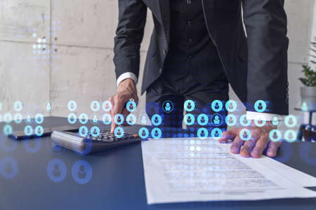 HR specialist researching and analyzing the data of salary on employment market to forecast ongoing expenses of the company using calculator. Hiring new talented officers. Social media hologram iconsの写真素材