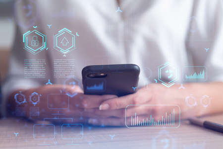 Businesswoman in formal wear holding in the hands a smart phone and testing an innovative...