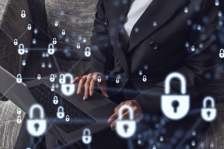 A woman programmer is typing a code on computer to protect a cyber security from hacker attacks and save clients confidential data. Padlock Hologram icons over the typing hands. Formal wear.の写真素材