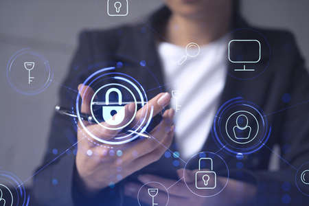 A woman programmer is browsing the Internet in smart phone to protect a cyber security from hacker attacks and save clients confidential data. Padlock Hologram icons over the typing hands. Formal wearの写真素材