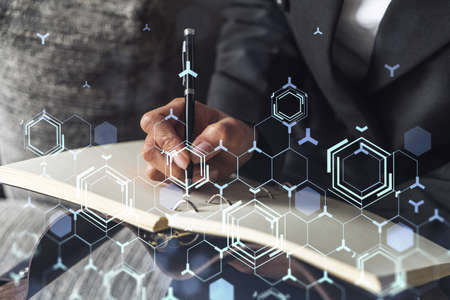 Businesswoman is writing down some ideas to create innovative software to change the world and provide a completely new service. Close up shot. Hologram tech graphs. Concept of Dev team. Formal wear.の写真素材