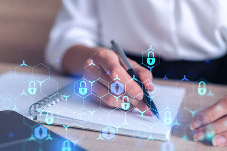 Businesswoman is taking notes of clients needs to protect cyber security from hacker attacks and save clients confidential data. Padlock Hologram icons over the typing hands. Formal wearの写真素材