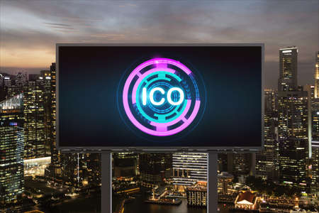 ICO hologram icon on billboard over panorama city view of Singapore at night time. The hub of blockchain projects in Southeast Asia. The concept of initial coin offering, decentralized financeの写真素材