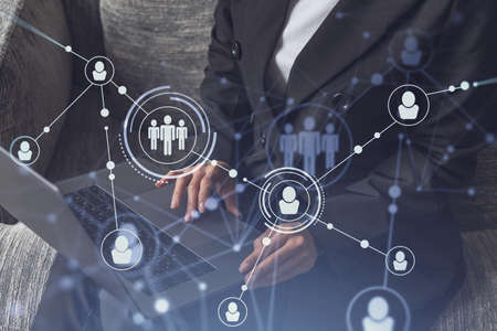 HR woman specialist is typing the keyboard in the internet to find the best candidates to create international network in recruitment process. Formal wear. Social media hologram icons.の写真素材