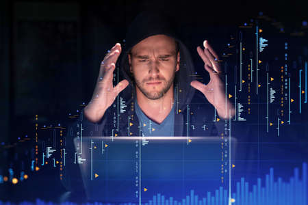 Handsome businessman in hoodie at workplace working with laptop to optimize trading strategy at...