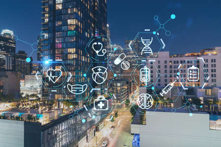 Illuminated cityscape of Los Angeles downtown at night, California, USA. Skyscrapers of LA city. Hologram healthcare digital medicine icons. The concept of treatment from disease, Threat of pandemicの写真素材