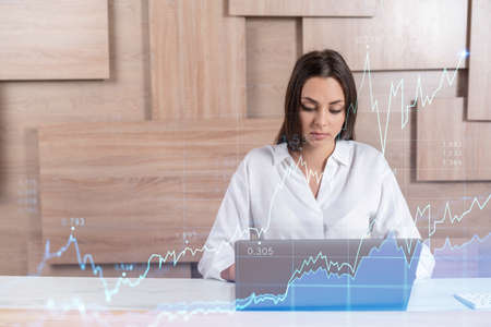 Attractive businesswoman in white shirt at workplace working with laptop to optimize trading...