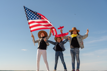 Independence Day. Three beautiful girls in cowboy hats with the American flag. The girl is holding a red plane.の写真素材