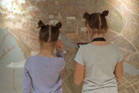 Girls in museum listening to interesting information about exhibit through headphones.