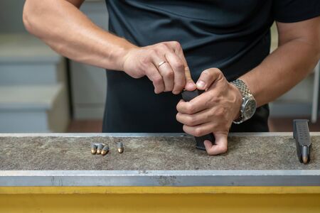 A man in a black T-shirt charges the pistol holder with 9 19 cartridges.のeditorial素材