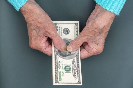 Poor elderly woman is counting some American Dollars in her hand. wrinkled Hands of an old woman....