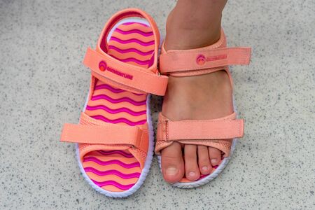 Russia, Kazan - August 10, 2019: old shoes new shoes on the girl s feet. Old dirty and new white sandalsのeditorial素材