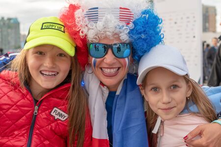 Russia, Kazan - August 27, 2019: close-up Portrait of a smiling fans: Two adorable Russian white kid girls and woman with a painted face in the colors of the Russian flag in the fan zone during the World Skills 2019 China Russia - Image. Russian patrioticのeditorial素材