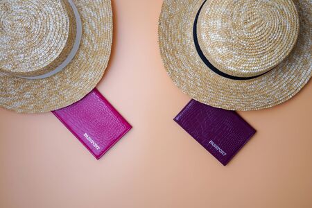 Two womens beach straw boater hats, passports on a beige background. Trip, travel and tourism conceptの写真素材