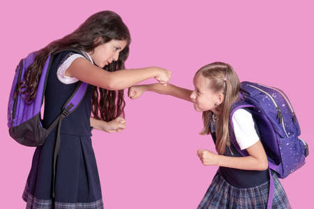 Two schoolgirls in school uniforms are fighting on a pink backgroundの写真素材