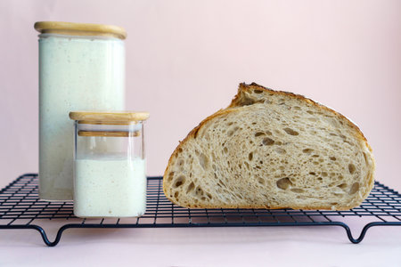 classic artisan tartine bread in a section, showing the airy crumb and wheat sourdough in jars....