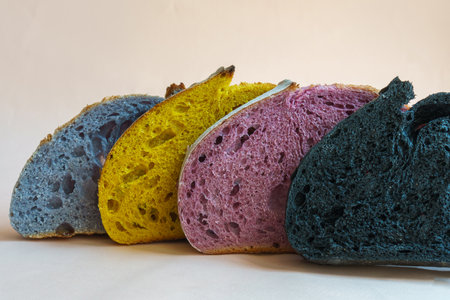 Fresh homebaked artisan colorful sourdough bread. Slices of bread isolated on pastel pink background, design element.の写真素材