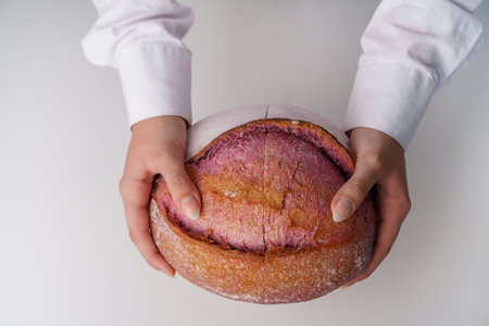Pink Unusual and creative colored artisan sourdough bread cut in the hands of a girl.