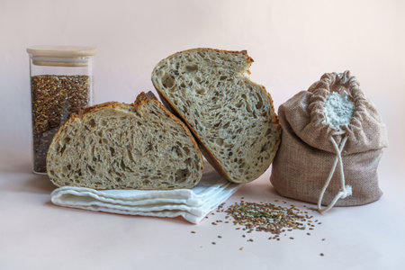 Handmade artisan bread with cutaway seeds, a bag of flour and wheat on a beige background.