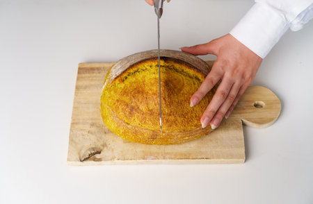 Flat-lay of female hands cutting freshly baked Unusual and creative colored artisan sourdough bread...