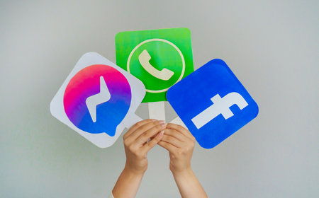 Girl Teen Hands Hold Facebook messenger, WhatsApp and Facebook logos on Gray background. Concept of Teenagers Using the Most Popular Social Networks. Turkey, Istanbul, September 17, 2024.のeditorial素材