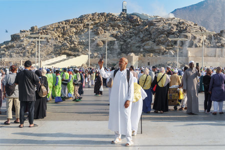 Close-up A male pilgrim in a white traditional Arab dress kandura takes a selfie with the holy mountain of Arafat in the background. Saudi Arabia, Mecca, November 23, 2024.のeditorial素材