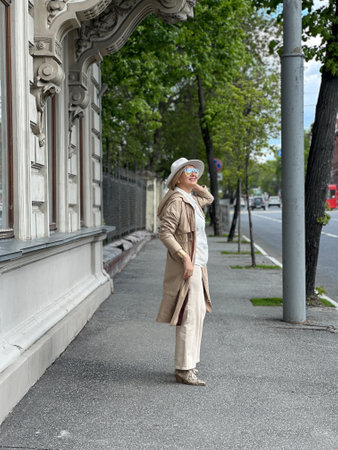 urban portrait of a middle-aged woman. Girl Dressed in a beige coat, hat and trousers.の写真素材