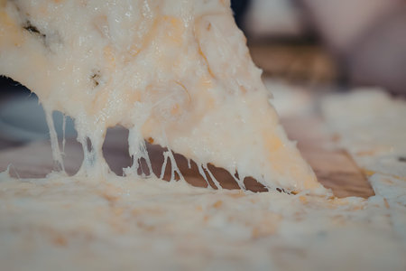 A close-up image of a slice of pizza being lifted, showcasing the gooey cheese strings.の写真素材