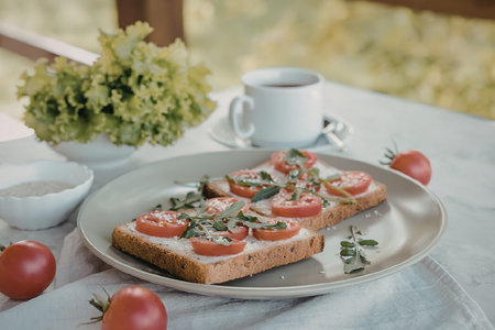 A plate of toast topped with fresh tomatoes and herbs, accompanied by a cup of coffee and a bowl of...