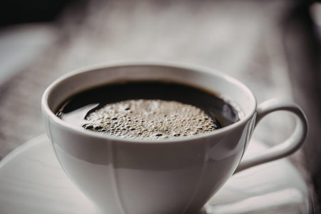 A white cup filled with black coffee on a matching saucer