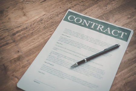 A contract document with a pen on a wooden table, ready for signing.