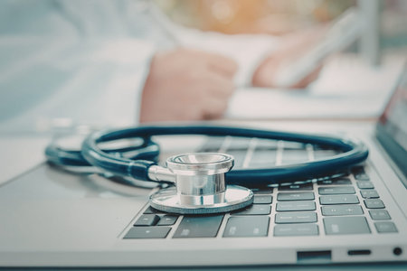 A stethoscope on a laptop keyboard with a doctor in the background