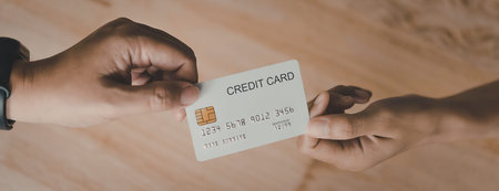 An image of two hands, one handing a credit card to the other