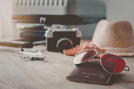 A collection of travel accessories, including sunglasses, a camera, a hat, and a typewriter,...