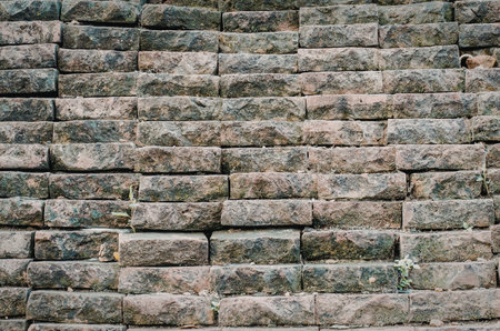 The image depicts a close-up view of a stone wall with visible signs of weathering and moss growth on its surface.の写真素材