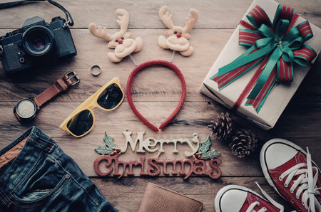 A collection of Christmas items including a gift, sunglasses, and a camera arranged on a wooden table.の写真素材