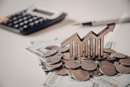 A pile of coins with a graph and calculator in the background representing financial growthの写真素材