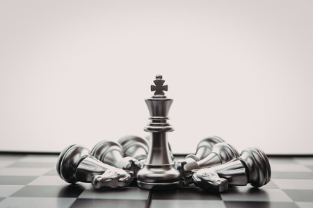 A chessboard with several fallen chess pieces around a standing king piece, conveying a sense of victory or resilience.の写真素材