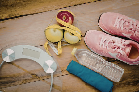 A collection of fitness and healthy lifestyle essentials including a scale, sneakers, water bottle,...