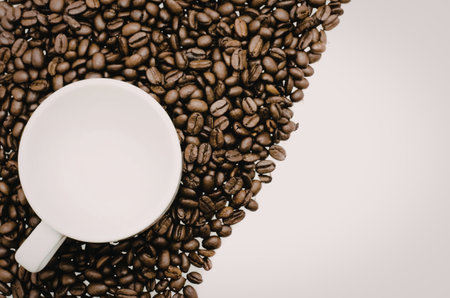A white coffee cup on a pile of roasted coffee beans