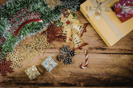 A festive arrangement of Christmas decorations on a wooden table, including tinsel, ornaments, candy cane, and gift boxes.の写真素材