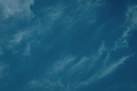 A serene blue sky with wispy clouds scattered across it, creating a beautiful and peaceful...