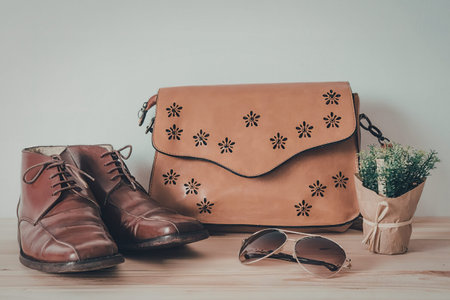 A brown leather bag with star designs, a pair of brown shoes, sunglasses, and a small potted plant...