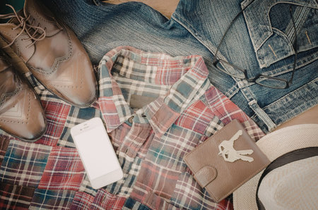 A collection of clothing items including a plaid shirt, jeans, boots, and a hat.