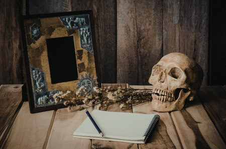 A still life composition featuring a human skull, an empty picture frame, and a spiral-bound...
