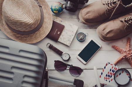 A collection of travel items including a suitcase, hat, shoes, phone, and accessories