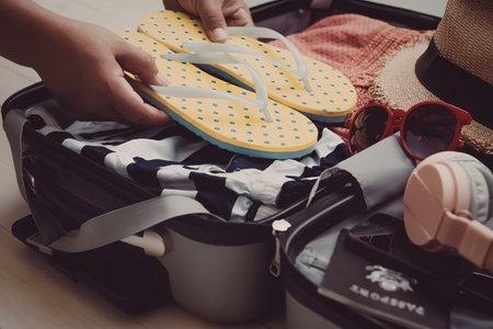 A person packing a suitcase with summer essentials